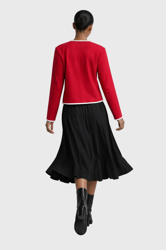 Person wearing a red sweater and black skirt on a white background