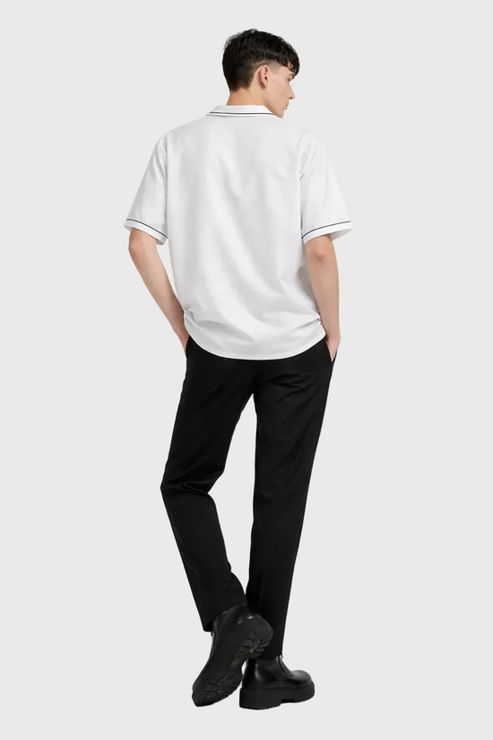 Person wearing a white polo shirt and black pants on a gray background