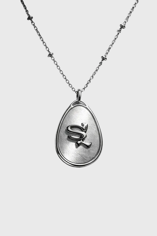 Silver necklace with a teardrop-shaped pendant on a gray background
