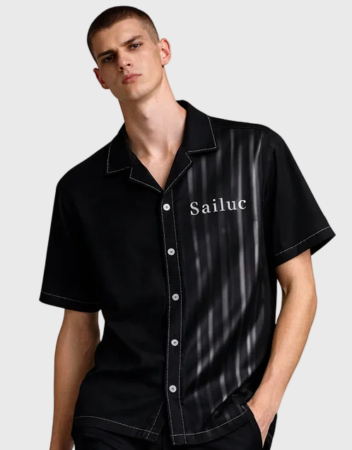Man wearing a black Hawaiian  with Sailuc branding on a gray background