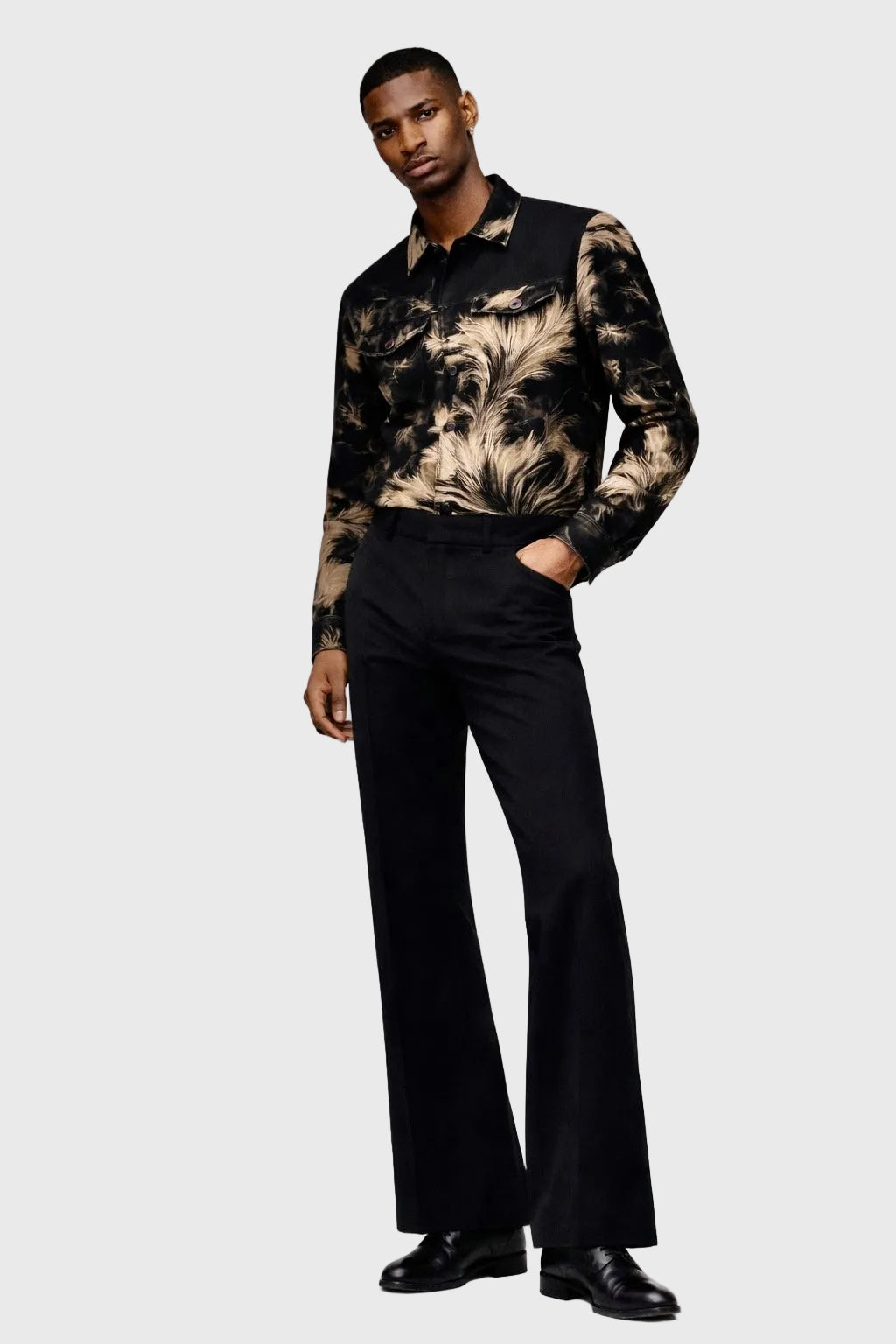 Man wearing a patterned jacket and black pants on a white background