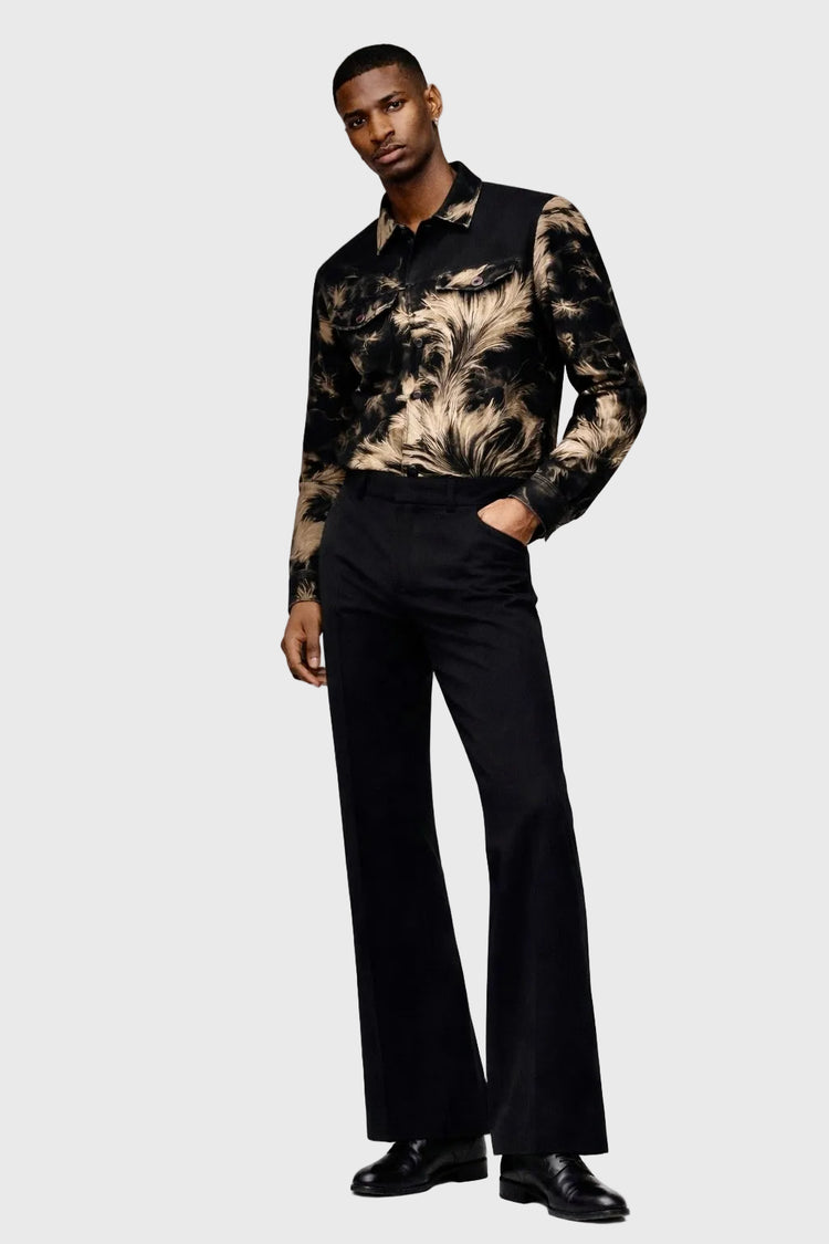 Man wearing a patterned jacket and black pants on a white background