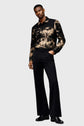 Man wearing a patterned jacket and black pants on a white background