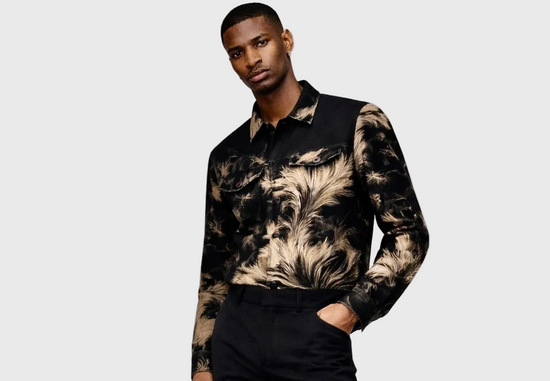 Man wearing a patterned jacket and black pants on a white background