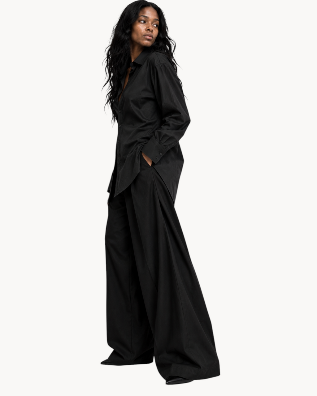 Model wearing a black Sailuc Linea longline shirt with a classic collar and lightweight fabric, paired with trousers.