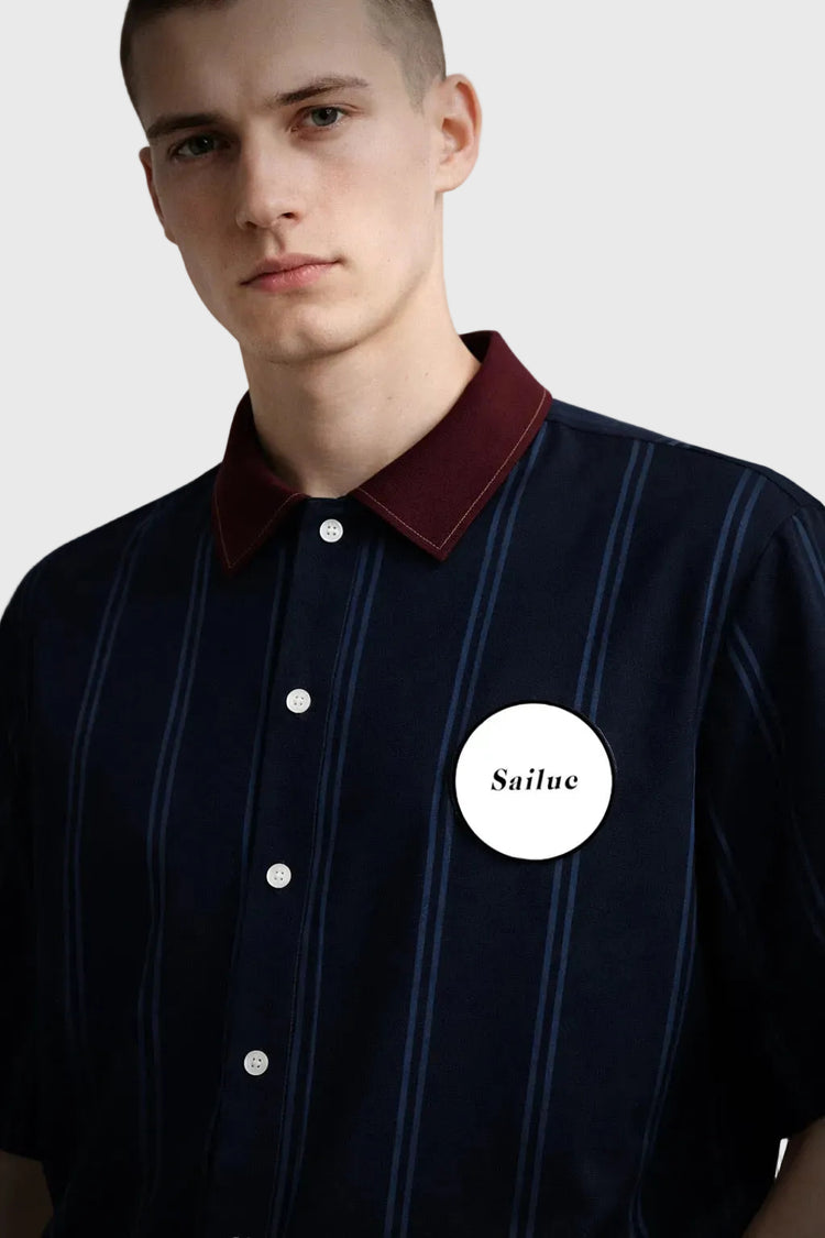 Man wearing a dark blue shirt with a maroon collar and &