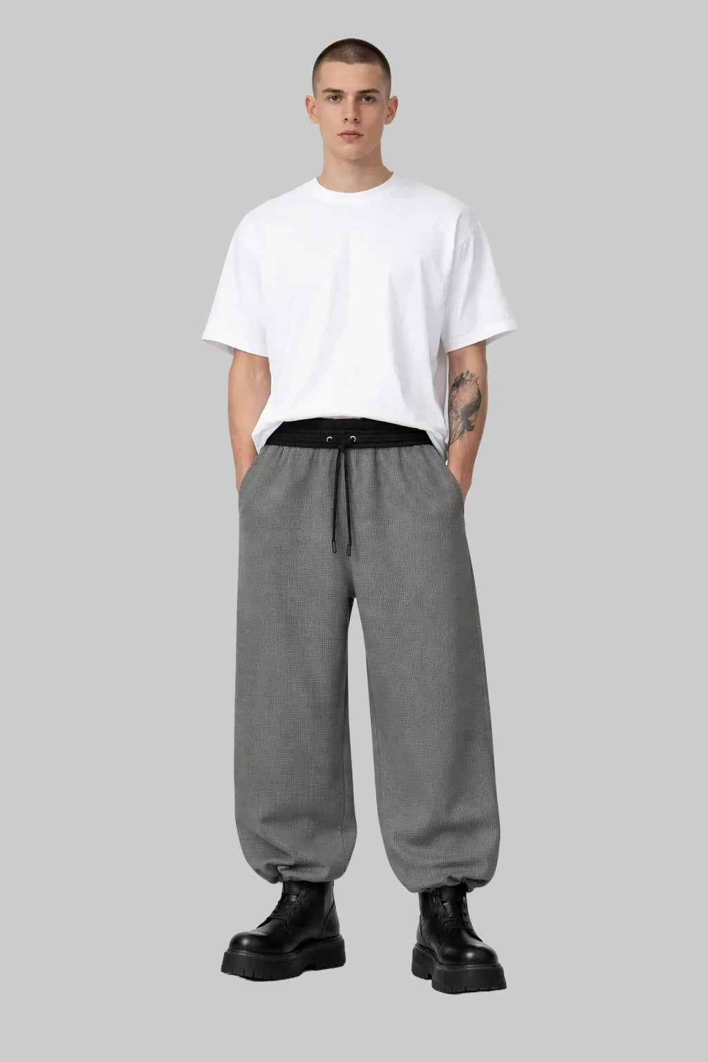 Man wearing Sailuc oversized white t-shirt, gray drawstring pants, and black boots