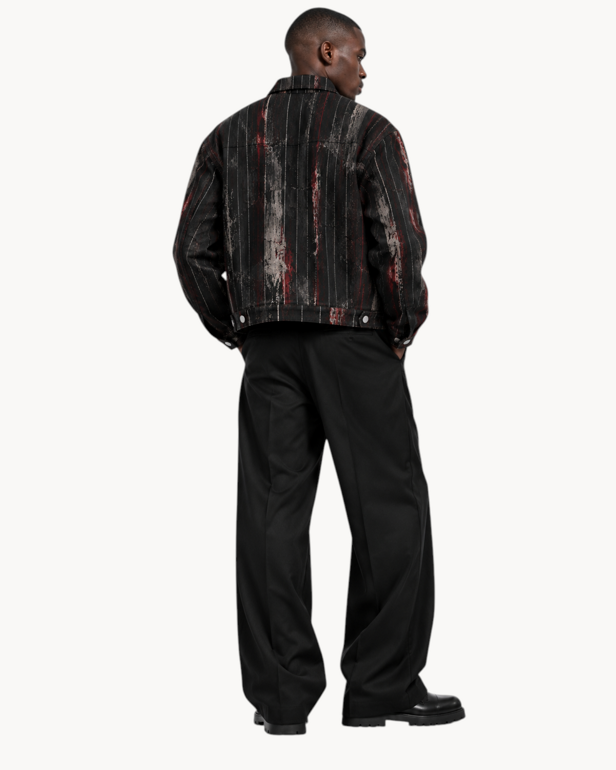 Model wearing a Sailuc Strata collared jacket with a textured, striped pattern and black trousers from behind.