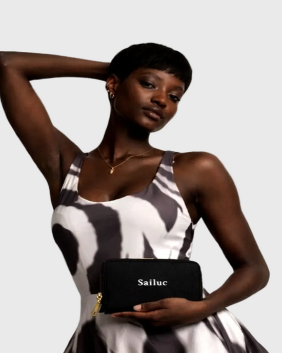 Woman holding a black clutch with Sailuc branding against a plain background