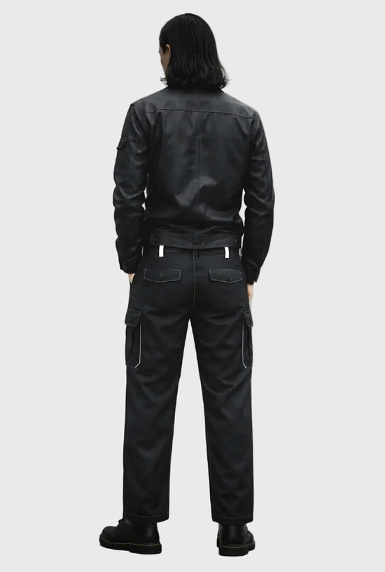 Person wearing a black leather jacket and pants on a gray background