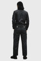 Person wearing a black leather jacket and pants on a gray background