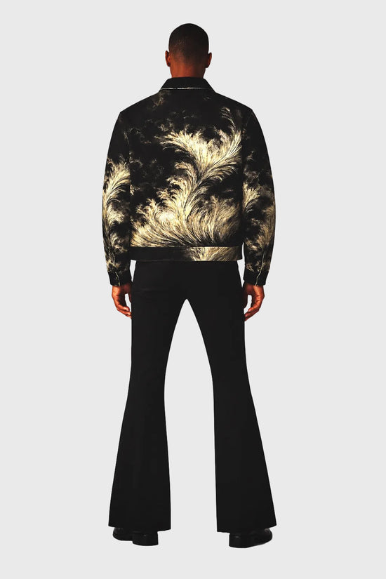 Person wearing a black feather-patterned jacket with black bell-bottom pants on a gray background