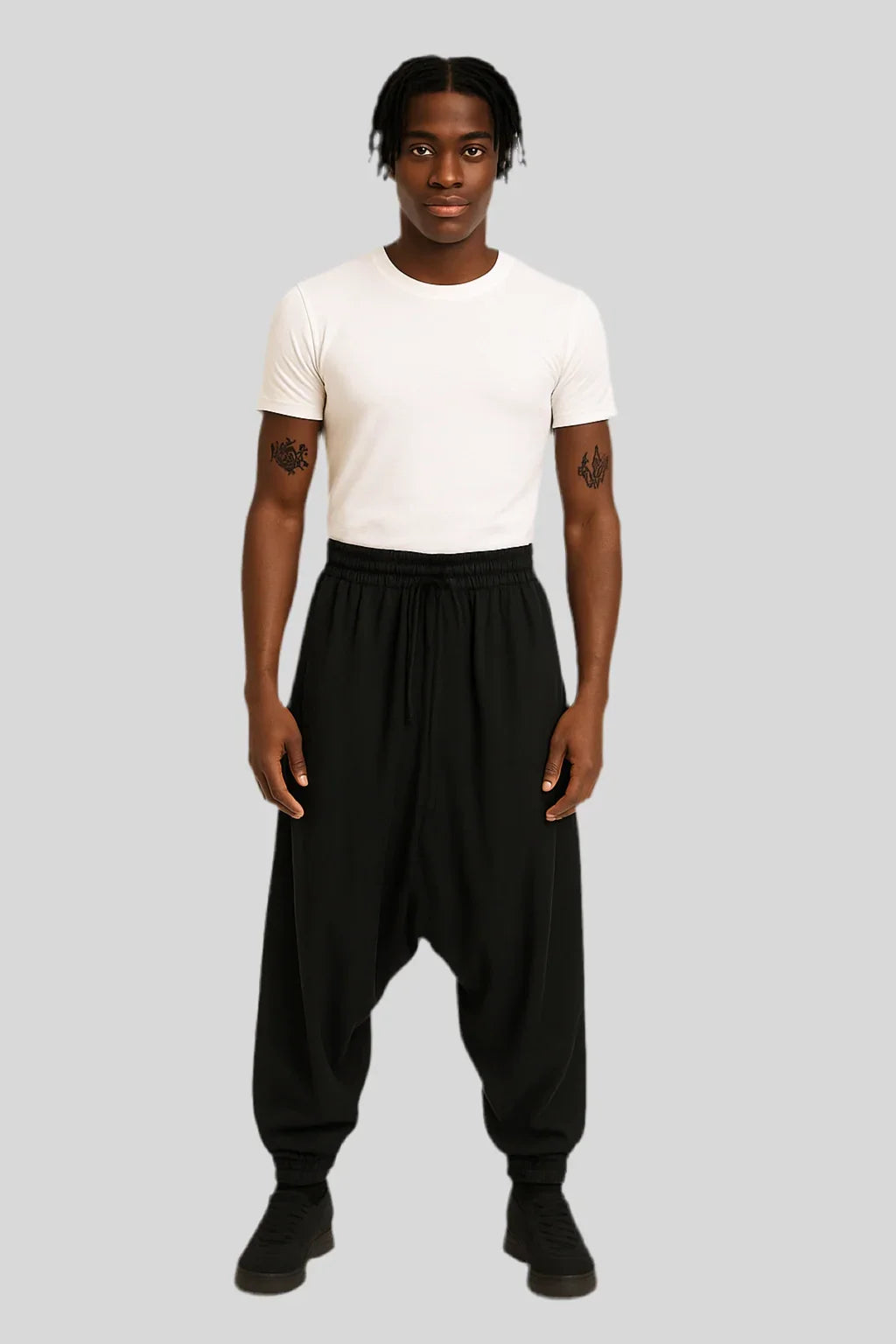 Man wearing Sailuc luxury black drop-crotch pants and white t-shirt on gray background