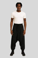 Man wearing Sailuc luxury black drop-crotch pants and white t-shirt on gray background