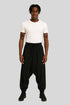 Man wearing Sailuc luxury black drop-crotch pants and white t-shirt on gray background