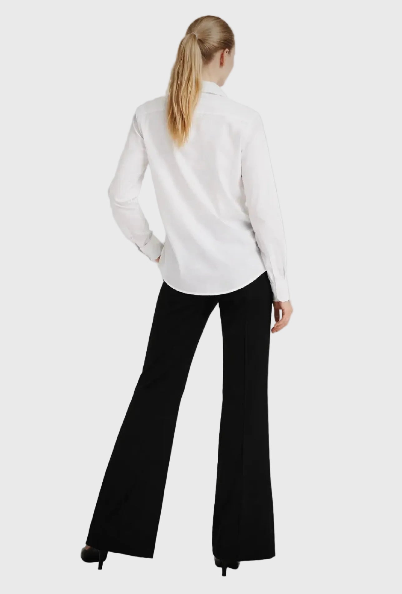 Person wearing a white blouse and black pants on a gray background