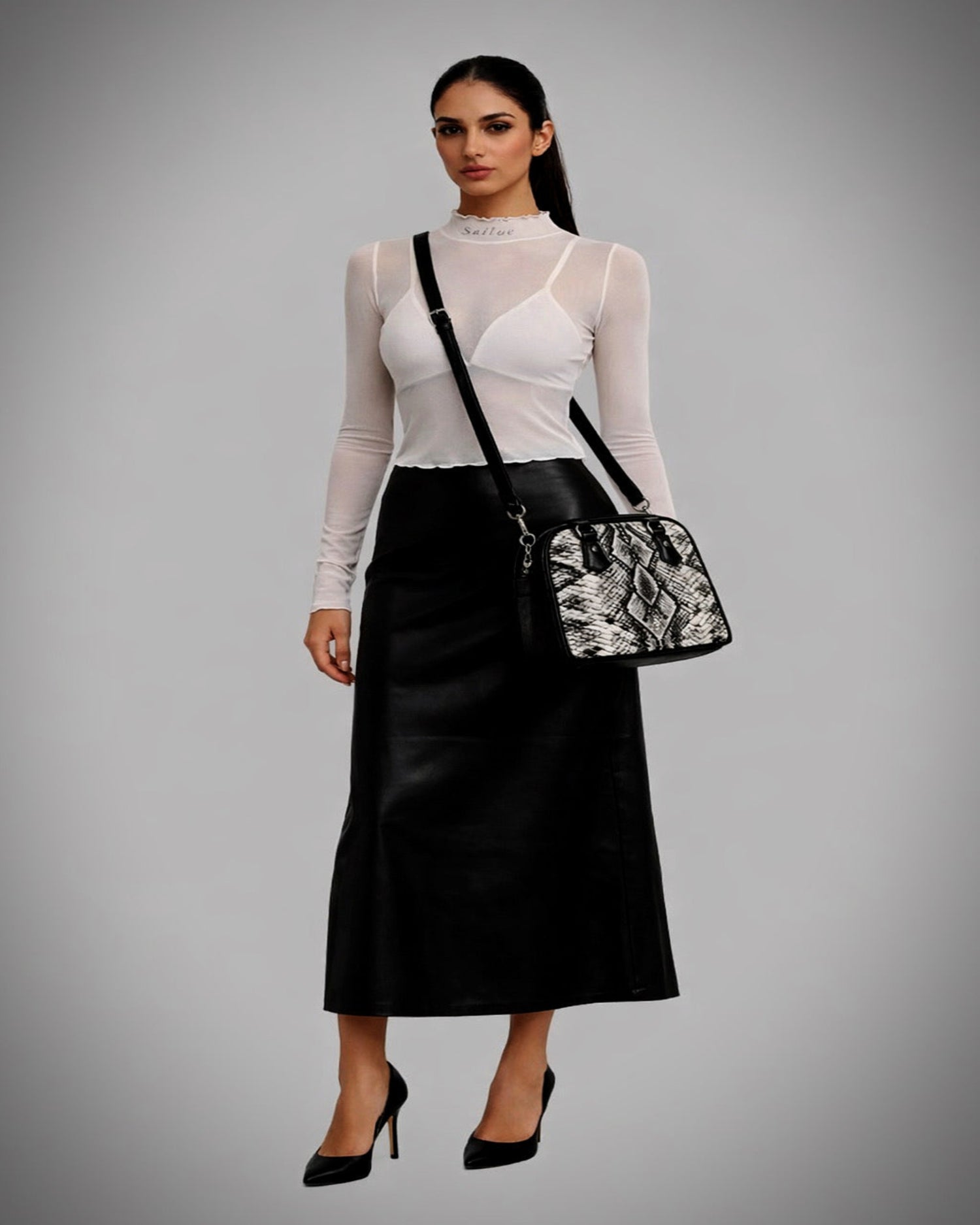 Woman wearing a black skirt and white top with a black and white patterned bag on a gray background