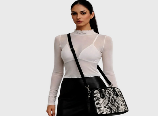 Woman holding a black handbag with lace detailing against a gray background