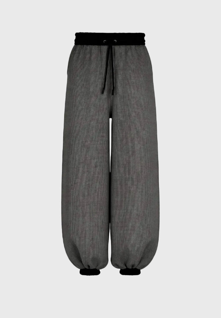 Gray pants with a black waistband and drawstring on a gray background