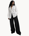 Model wearing a Sailuc white longline shirt with a classic collar and black wide-leg trousers against a white backdrop