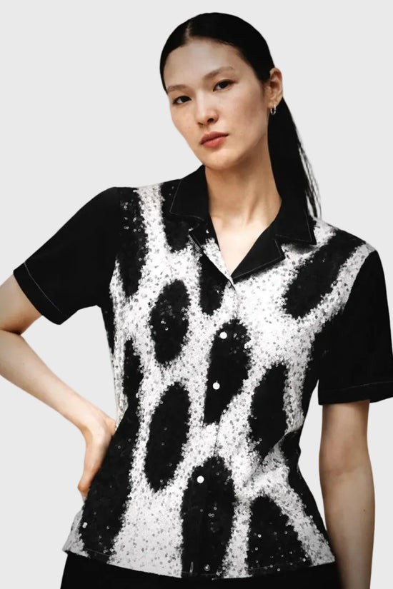 Woman wearing a leopard patterned shirt against a gray background