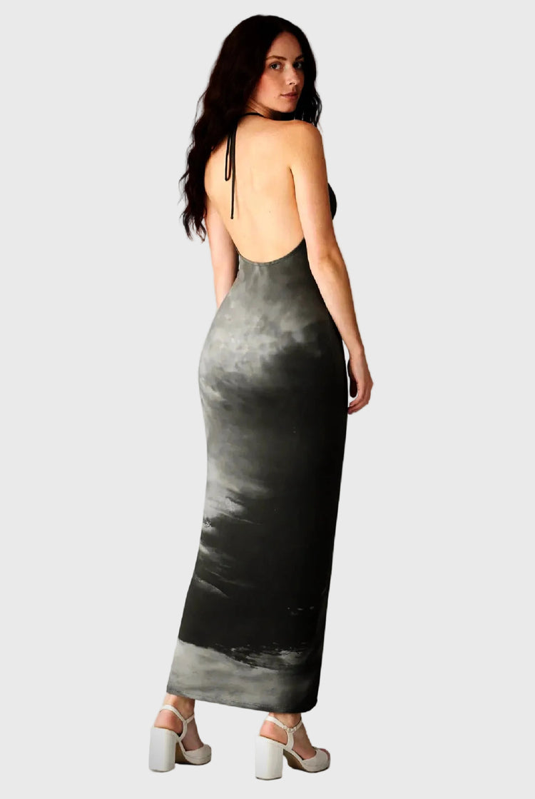 Woman wearing a long, dark sky dress with thin straps on a gray background