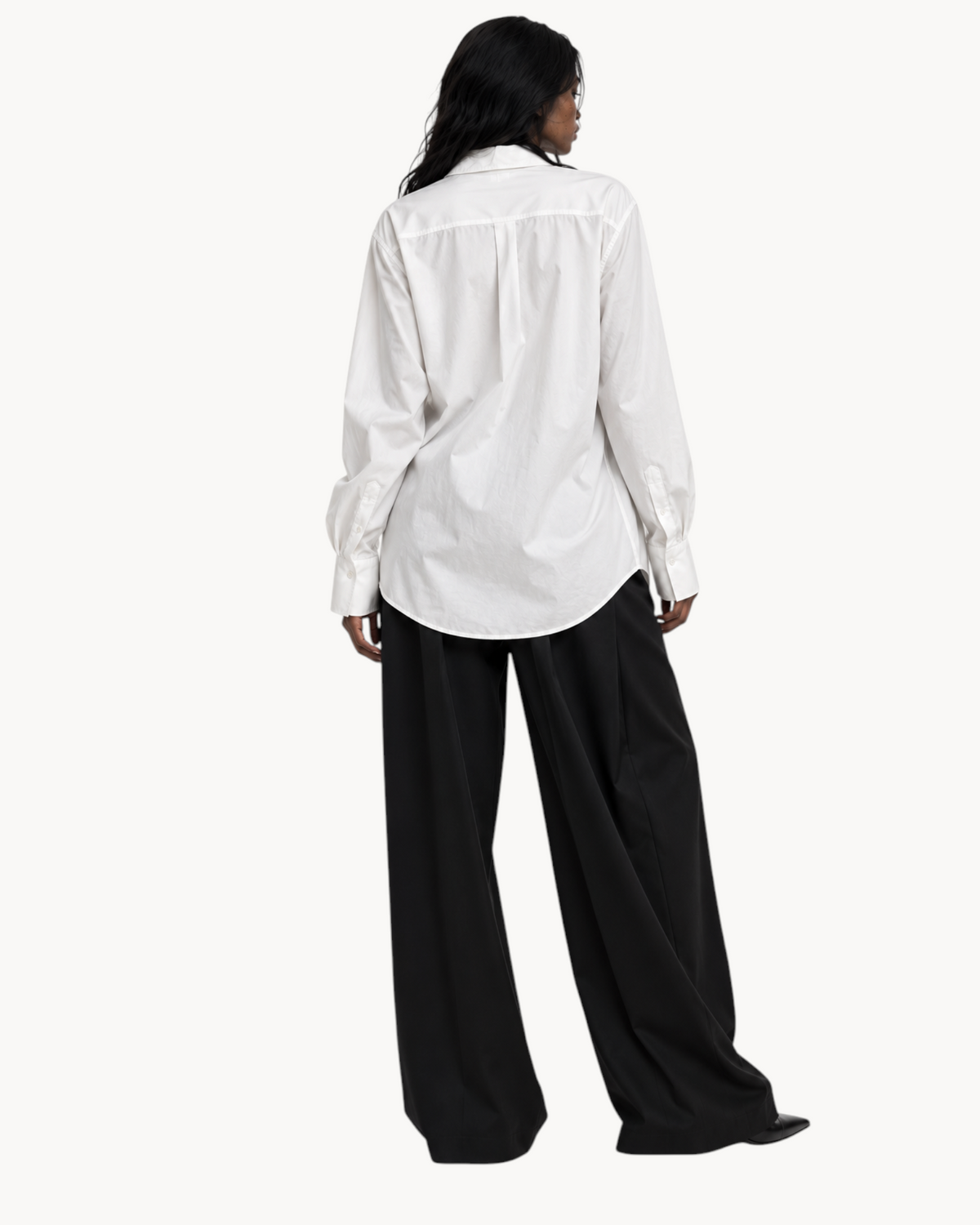 Model wearing a Sailuc white longline shirt with a classic collar and loose fit paired with black wide-leg trousers.