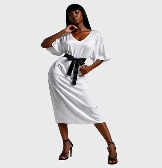 Woman wearing a white dress with a black belt on a gray background