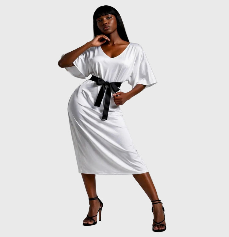 Woman wearing a white dress with a black belt on a gray background