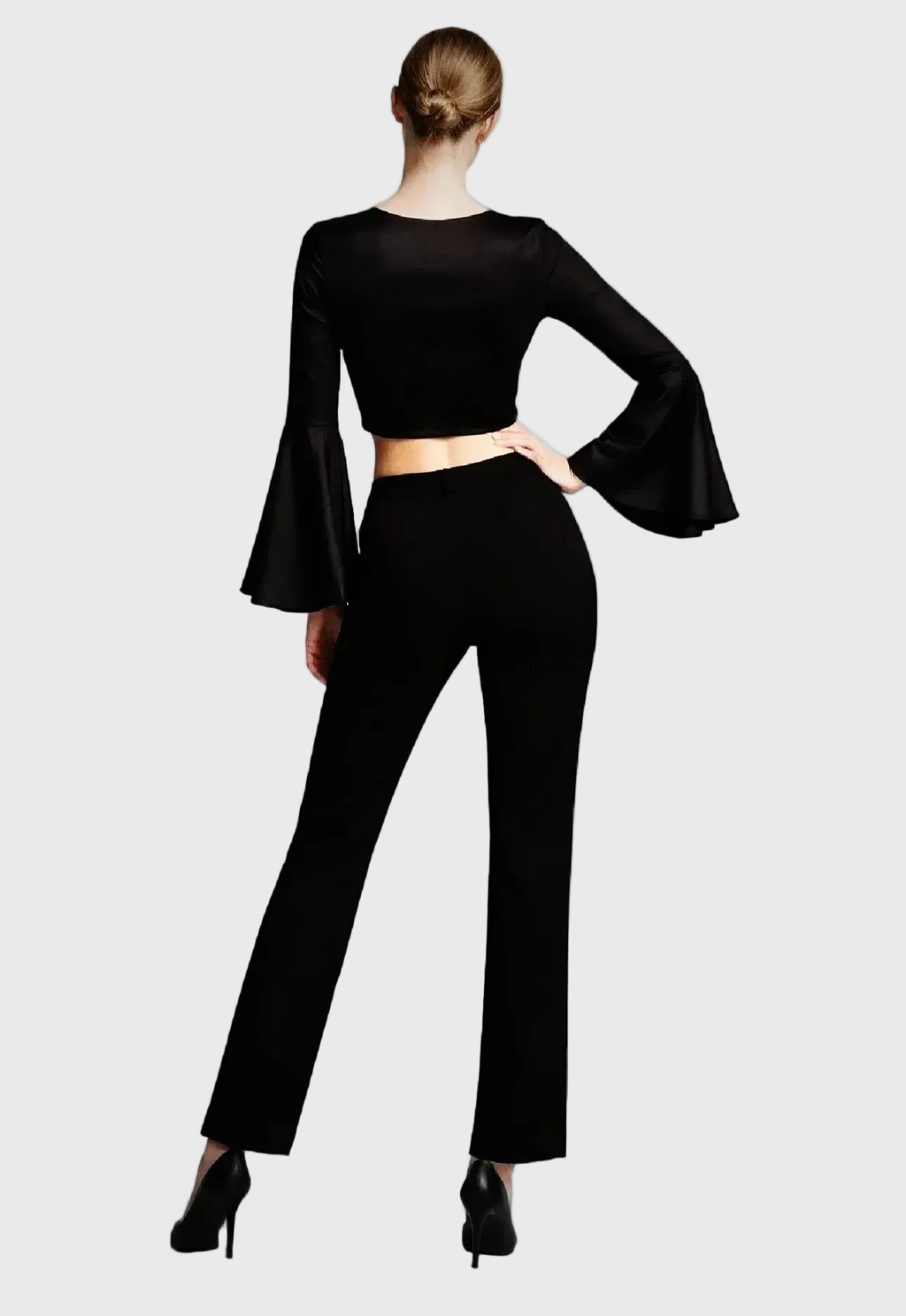 Person wearing a black outfit with bell sleeves on a cream background