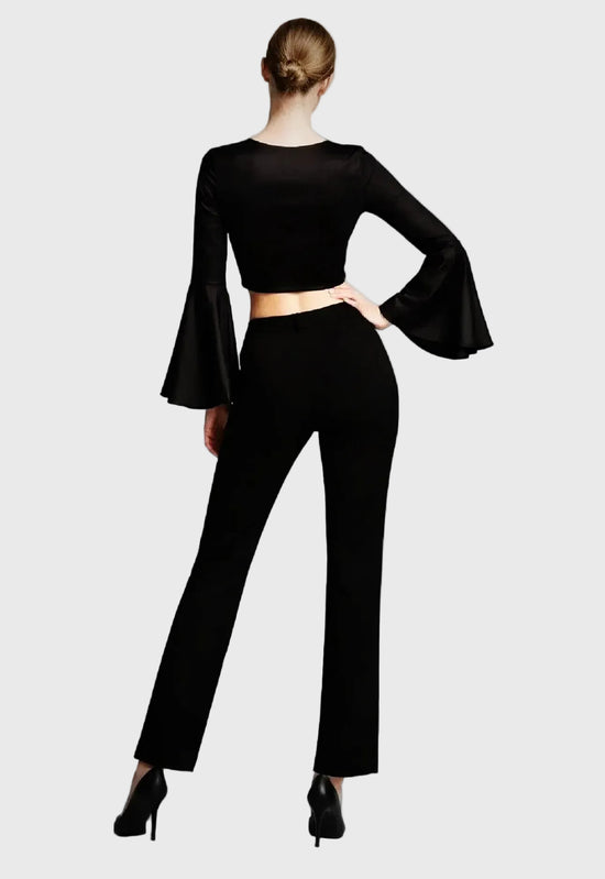 Person wearing a black outfit with bell sleeves on a cream background