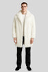 Man wearing Sailuc luxury white faux fur coat, black pants, and black shoes on gray background