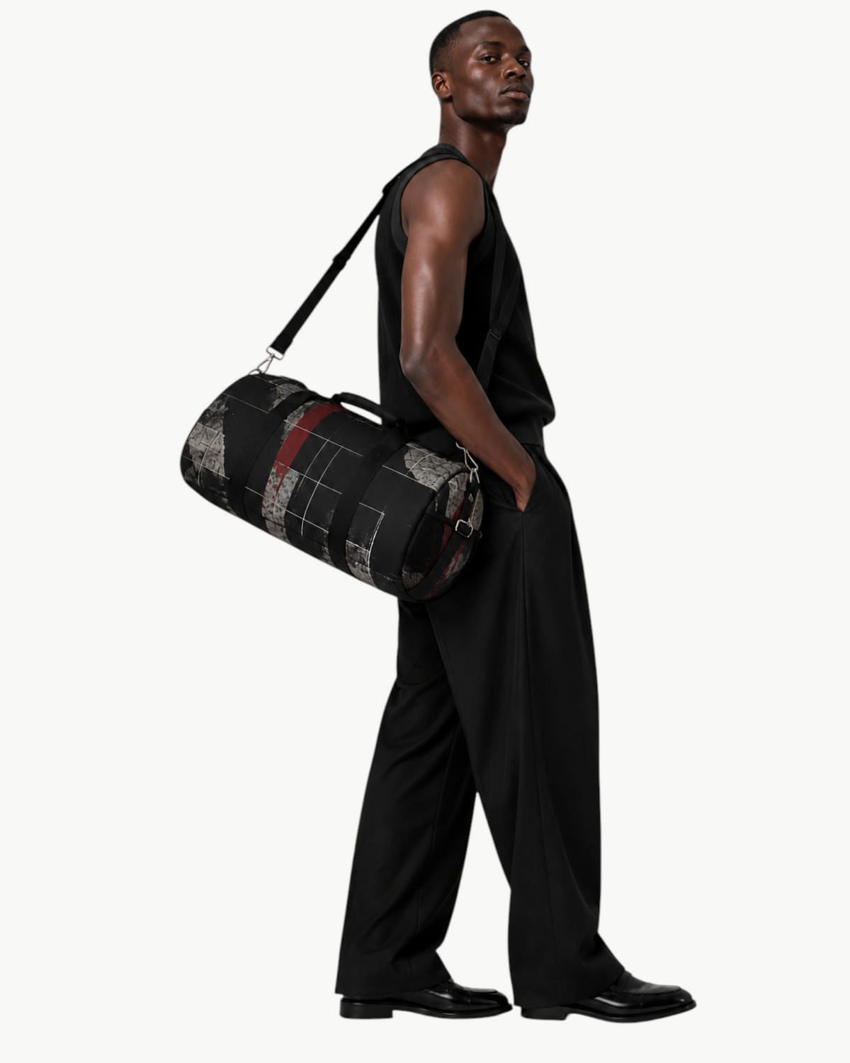Model carrying a Sailuc Obscura duffle bag in dark abstract canvas with brushed nickel hardware and shoulder strap.
