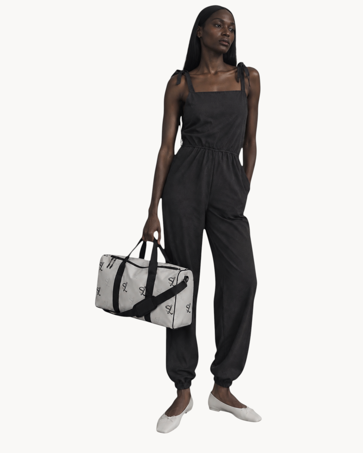 Model holding a white Sailuc Essential Voyage Bag with black monogram print, black handles, and black hardware.