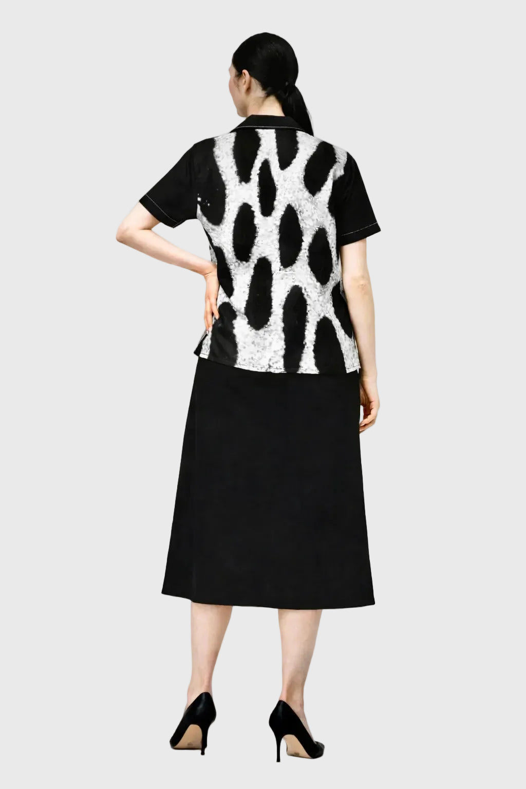 Person wearing a leopard patterned top and black skirt on a gray background