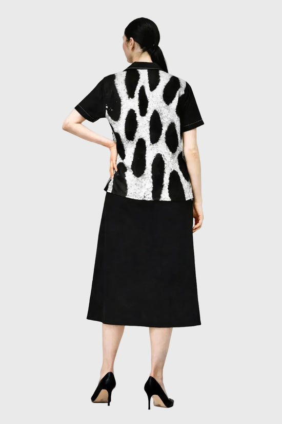 Person wearing a leopard patterned top and black skirt on a gray background