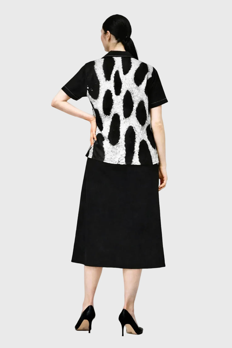 Person wearing a leopard patterned top and black skirt on a gray background
