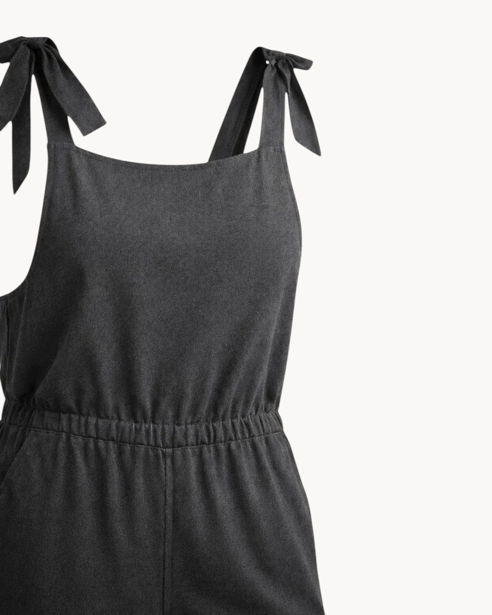 charcoal  jumpsuit with bow straps on a gray background