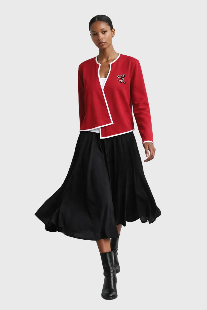Woman wearing a red top black skirt, and black boots on a gray background
