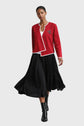 Woman wearing a red top black skirt, and black boots on a gray background