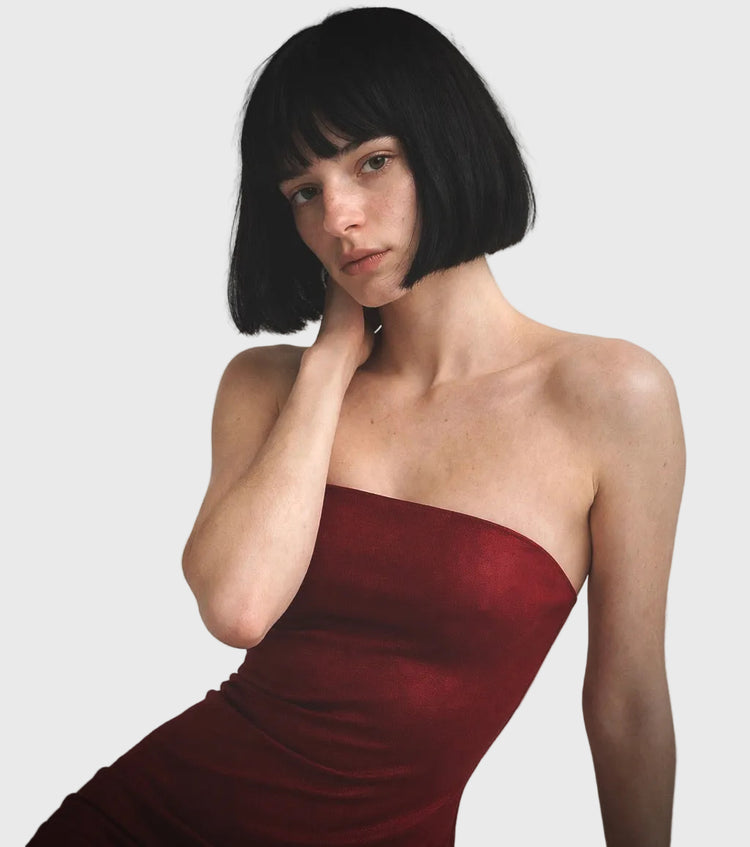 Woman wearing a strapless red dress against a gray background