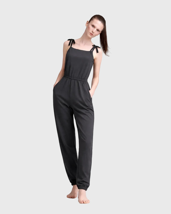 Woman wearing a charcoal jumpsuit on a light gray background