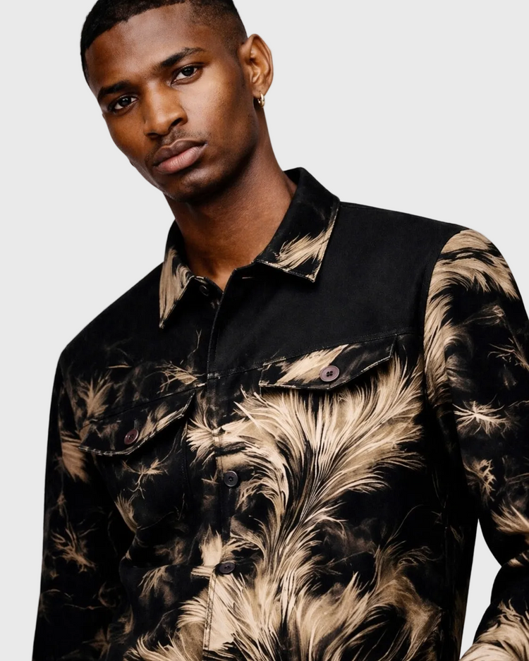 Man wearing a black jacket with feather pattern on a plain background