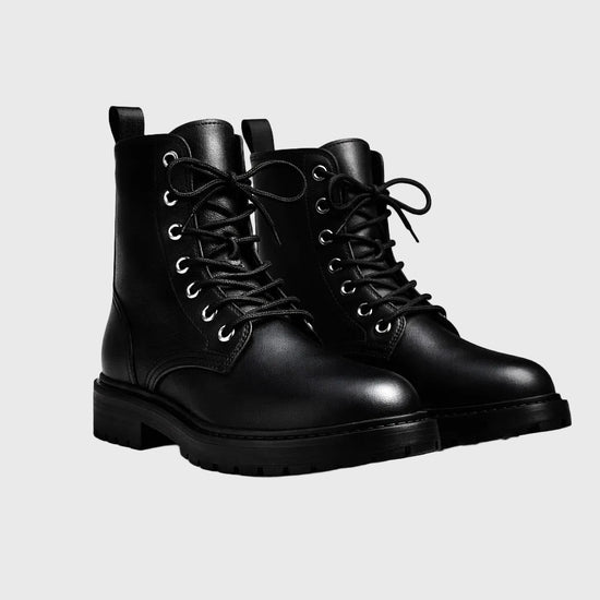 Pair of black leather boots on a gradient gray background