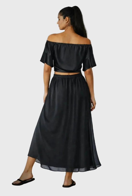 Woman wearing a black off-shoulder top and skirt set on a gray background