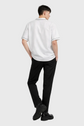 Person wearing a white polo shirt and black pants on a gray background