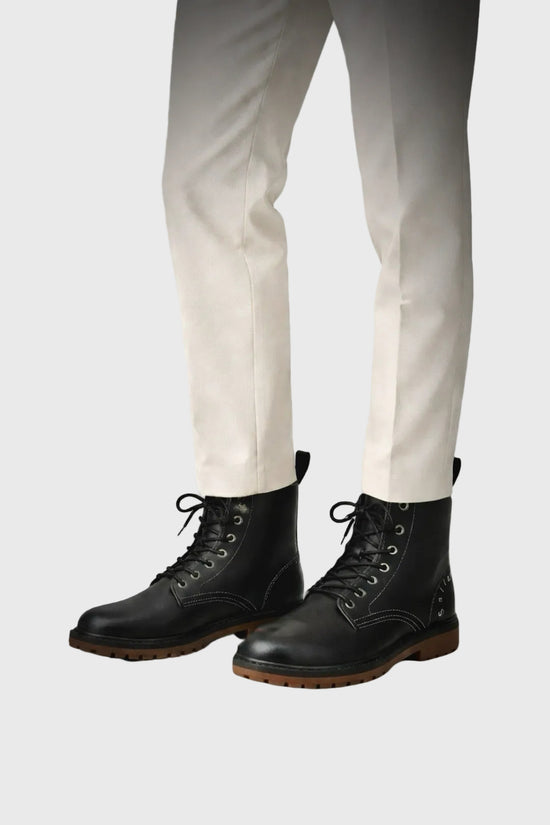 Black boots worn with white pants on a gray background