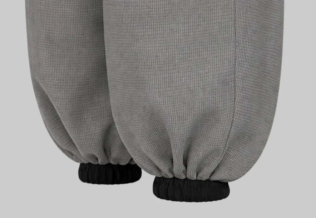 Close-up of Sailuc grey jogger pants with elastic black cuffs, luxury menswear fashion.