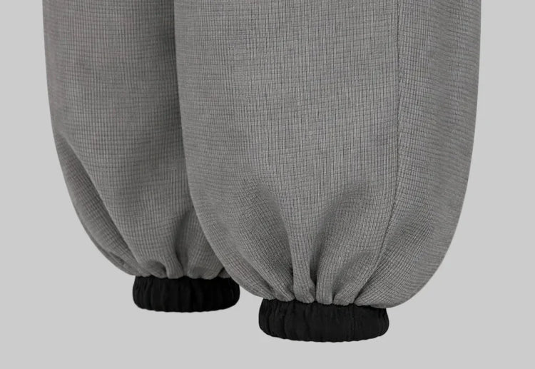 Close-up of Sailuc grey jogger pants with elastic black cuffs, luxury menswear fashion.