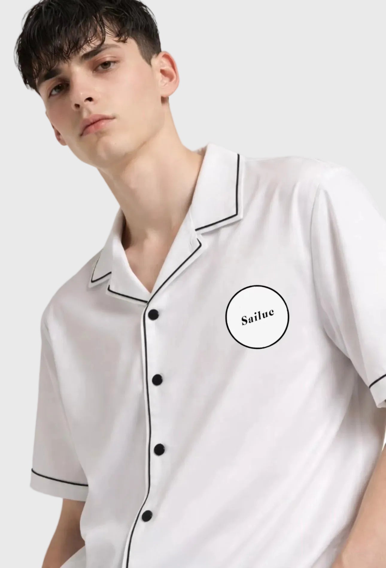 Person wearing a white short-sleeve shirt with black trim and logo on a gray background